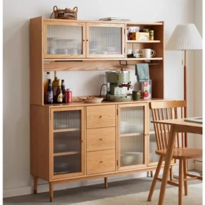 Front view of a solid oak sideboard with fluted glass cabinet doors and drawers, styled as a coffee station in a bright dining room.