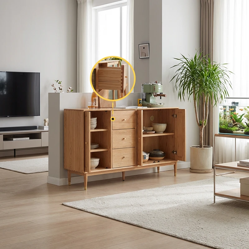 Lifestyle view of a solid oak sideboard with folding doors open to reveal shelves, three drawers and brass capped tapered legs in a living room.