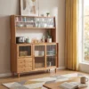 manna-oak-sideboard-glass-cabinet-coffee-station-living-room Lifestyle view of an oak sideboard hutch with fluted glass sliding doors and drawers, styled with a toaster beside a low table with books.