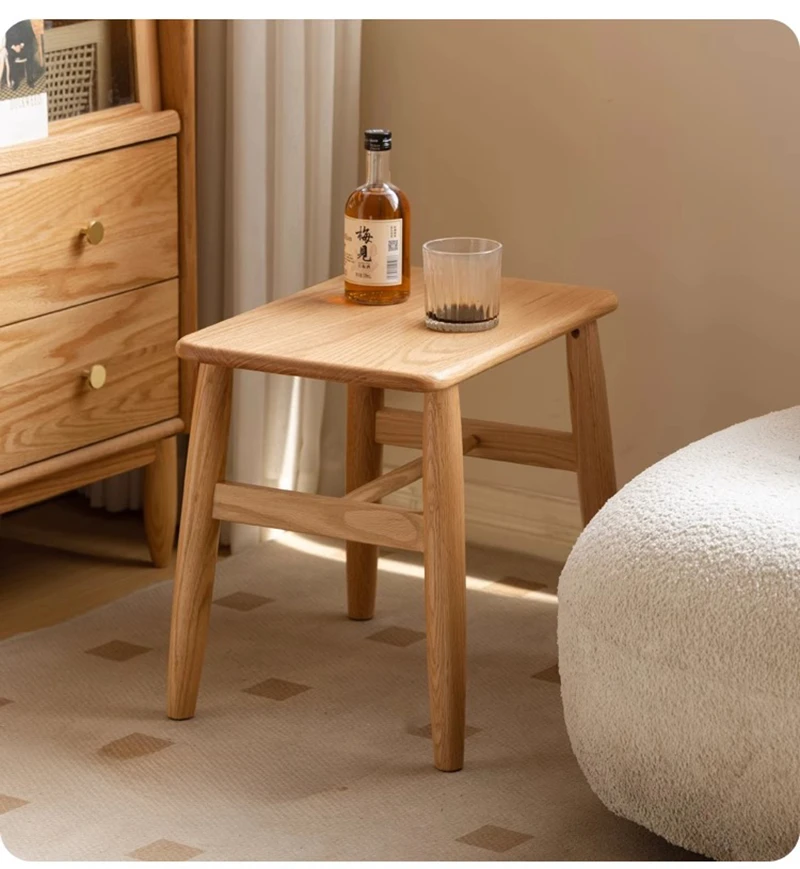manna-oak-square-stool-side-table-lifestyle Tall solid oak square stool used as a side table holding a bottle and glass beside a white boucle pouf.