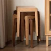 manna-oak-stool-nested Four solid wood square stools in light oak and dark walnut finishes nested together in a stack in a corner.