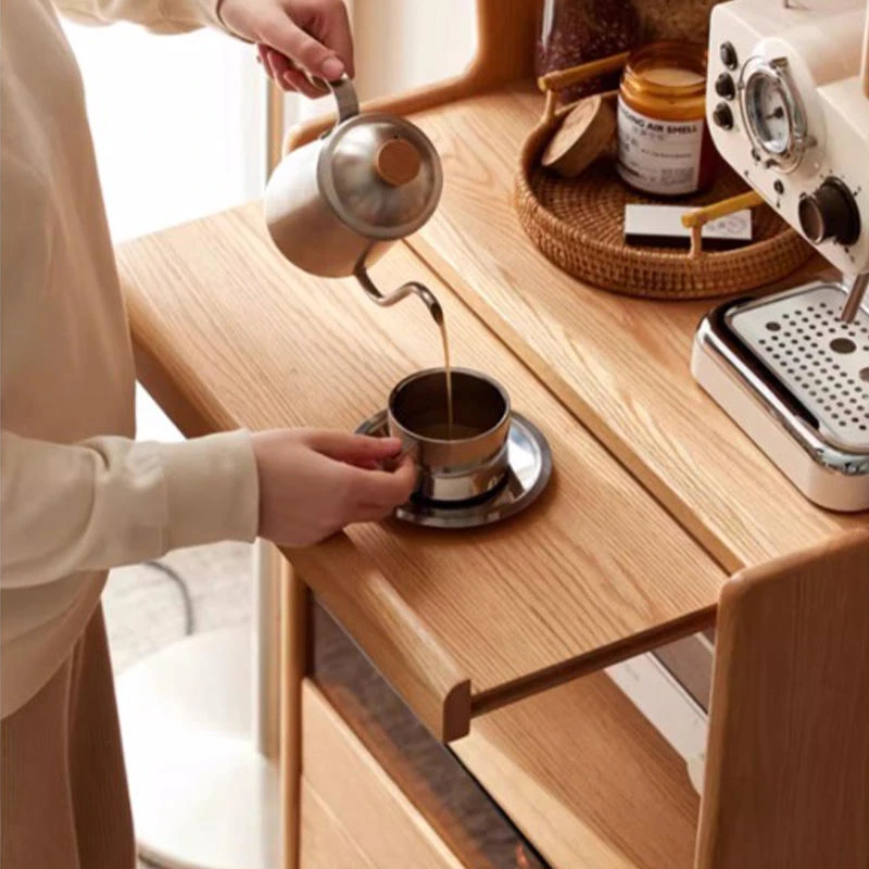 manna-oak-tall-sideboard-coffee-bar-lifestyle Lifestyle view of an oak tall sideboard coffee bar with a gooseneck kettle pouring into a metal cup on the pull-out shelf.
