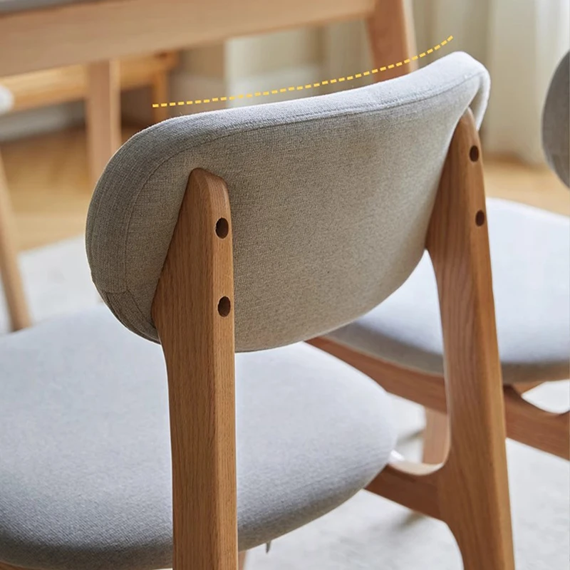 manna-oak-upholstered-dining-chair-grey-detail Detail view of the grey fabric upholstered backrest and oak frame joints of a curved back dining chair.
