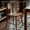manna-walnut-dining-chair-assembly Walnut dining chair shown fully assembled with mortise and tenon joints in a dining room with a sideboard and rug.