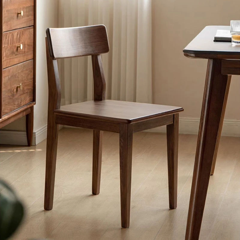 manna-walnut-dining-chair-curved-back-main Full view of a solid walnut dining chair with a curved backrest and contoured wooden seat in a bright dining room.