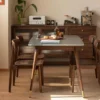 Lifestyle view of two solid walnut dining chairs with curved backrests set at a grey marble dining table in a warm dining room.