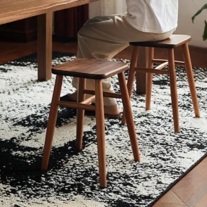 manna-walnut-dining-stool-dining-room Lifestyle view of small wooden dining stools with black walnut seats and oak legs used beside a table on a patterned rug.