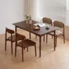 Lifestyle scene of a rectangular walnut dining table with four chairs beside a large window with blinds.