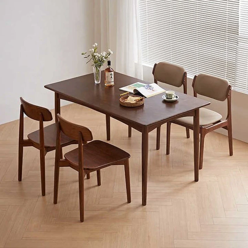 Lifestyle scene of a rectangular walnut dining table with four chairs beside a large window with blinds.