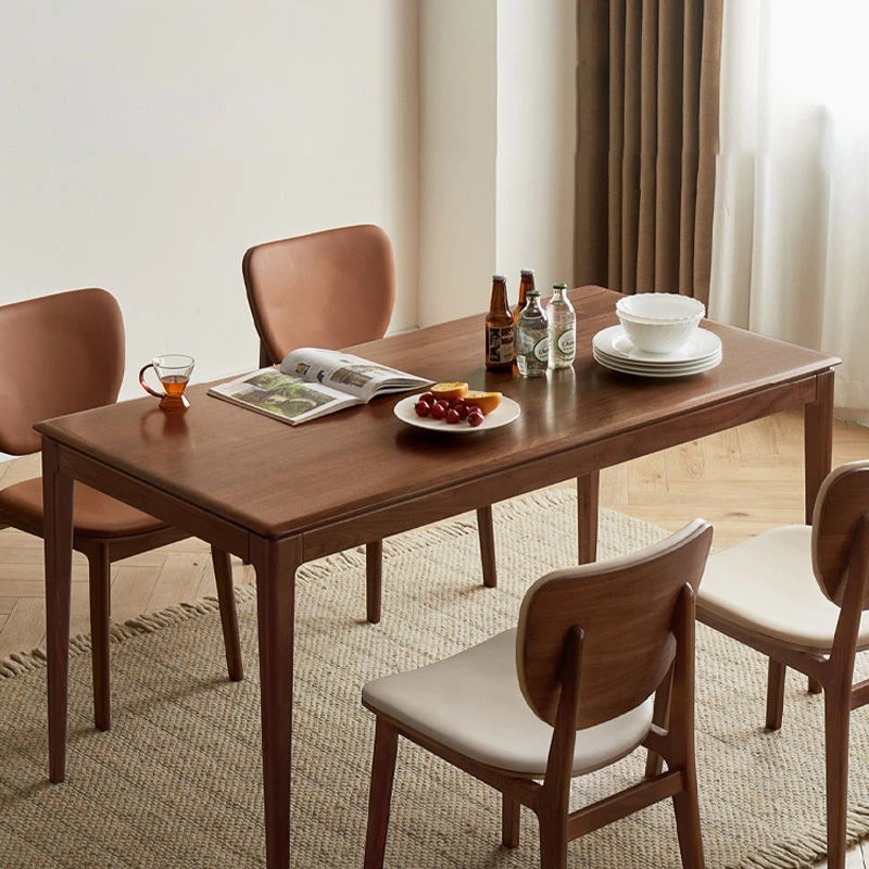 Bright living room with a rectangular walnut dining table, black leather chairs and cream upholstered chairs on a woven rug.