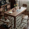 manna-walnut-rectangular-dining-table-with-serving-trolley-living-room Living room scene with a long walnut dining table, wood chairs and a two tier serving trolley on a dotted rug.