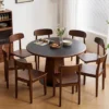 manna-walnut-round-dining-table-120cm-main Main view of a round walnut dining table with black top and hexagonal wood pedestal base in a bright dining room.