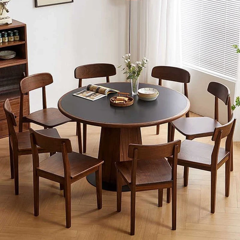 manna-walnut-round-dining-table-120cm-main Main view of a round walnut dining table with black top and hexagonal wood pedestal base in a bright dining room.
