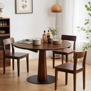 manna-walnut-round-pedestal-dining-table-lifestyle Lifestyle scene of a round walnut pedestal dining table with two wood chairs beside a window and herringbone oak floor.