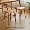 manna-walnut-square-stool-pair-dining-room Two solid walnut square stools with rounded seats standing under a wooden dining table on a light oak floor.