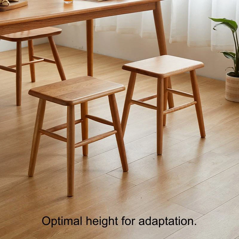 manna-walnut-square-stool-pair-dining-room Two solid walnut square stools with rounded seats standing under a wooden dining table on a light oak floor.