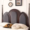 Arched upholstered headboard carved post detail on a dark cherry bed
