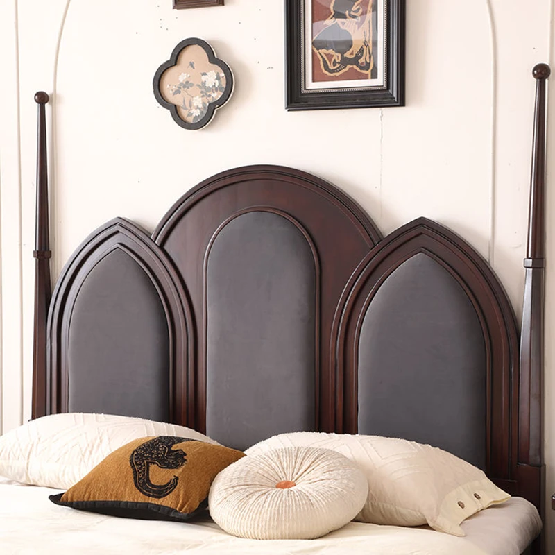 Arched upholstered headboard carved post detail on a dark cherry bed