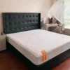 Black leather tufted headboard closeup beside a white nightstand