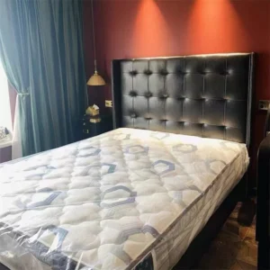 Black leather upholstered platform bed with wingback headboard in a bedroom scene