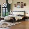 Black upholstered bed side view with matching wavy nightstand