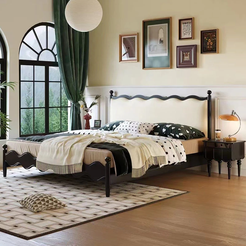 Black upholstered bed side view with matching wavy nightstand
