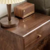 Black walnut 2 drawer nightstand beside bed with warm table lamp