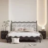 Black wood bed with wavy headboard and printed panels in a modern bedroom scene