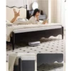Black wood upholstered bed with cream wavy headboard in a cozy lifestyle reading scene