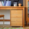 Cherry wood drawer unit on casters tucked under a desk side view