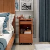 Cherry wood narrow rolling nightstand with glass top in bedroom