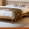 Natural oak spindle platform bed frame styled in a cozy bedroom with soft bedding