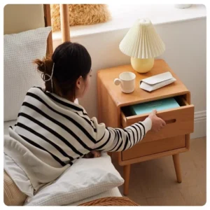 Natural oak nightstand with two drawers beside a bed in a warm styled bedroom