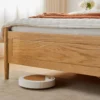 oak-bed-frame-robot-vacuum-clearance-detail Robot vacuum cleaning under the oak bed frame showing generous ground clearance