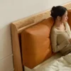 Oak platform bed with tan leather cushion headboard in a warm lifestyle bedroom scene