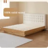 Solid oak bed frame with cream tufted headboard and wood slatted base in a bright room