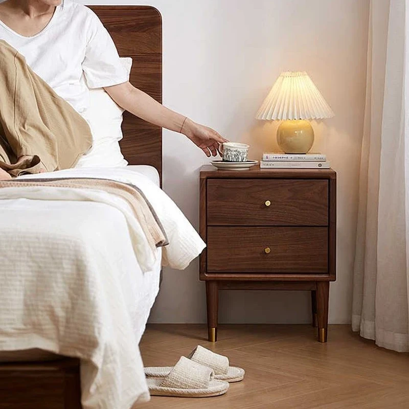 Walnut nightstand with two drawers beside a lamp in a warm bedside scene