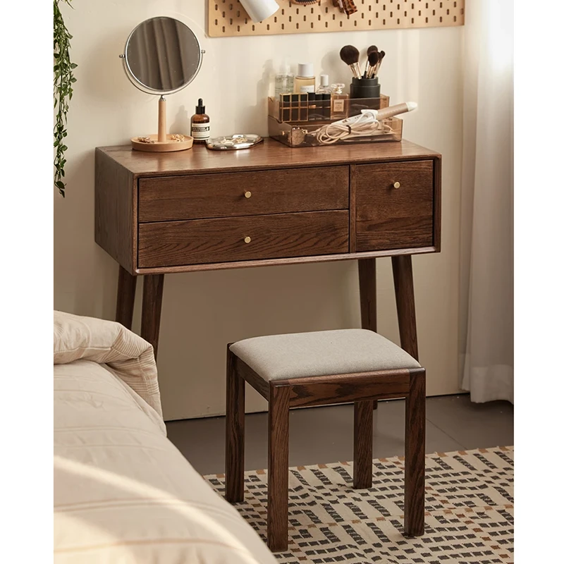 Wooden vanity stool tucked under dressing desk in room scene